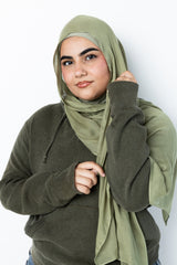 woman wearing modal hijab in different sizes in an olive green tone