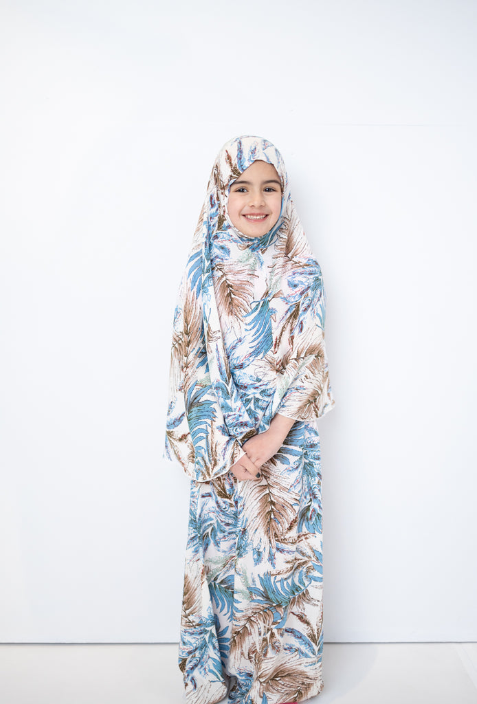 two piece salah outfit with hijab and skirt printed with blue, white, and beige leaves