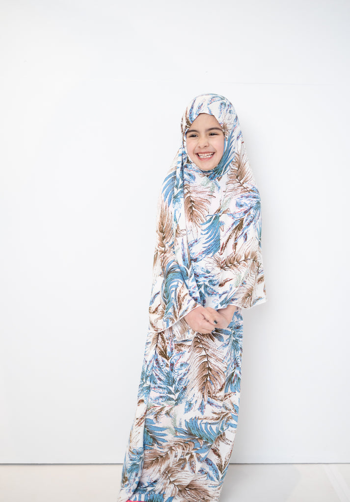 two piece salah outfit with hijab and skirt printed with blue, white, and beige leaves