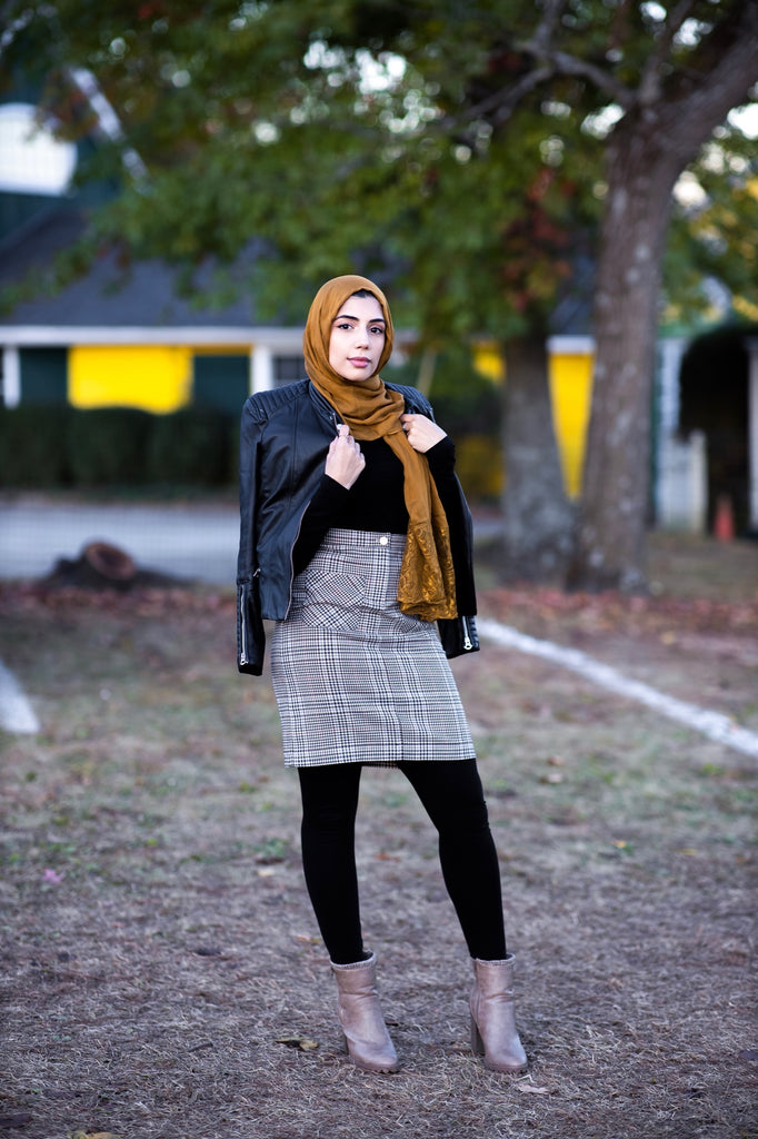 muslim woman wearing a mocha brown modal lace hijab modal hijab with lace on the ends and a leather bomber jacket and pencil checkered skirt