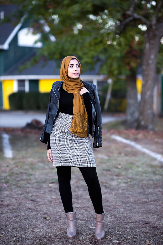 muslim woman wearing a mocha brown modal lace hijab modal hijab with lace on the ends and a leather bomber jacket and pencil checkered skirt