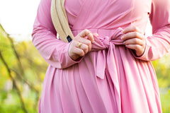 muslim woman wearing a gold shimmer jersey hijab and pink criss cross maxi long sleeve dress with pockets and a waist tie