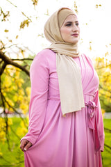 muslim woman wearing a gold shimmer jersey hijab and pink criss cross maxi long sleeve dress with pockets and a waist tie