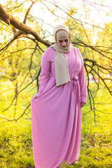 muslim woman wearing a gold shimmer jersey hijab and pink criss cross maxi long sleeve dress with pockets and a waist tie