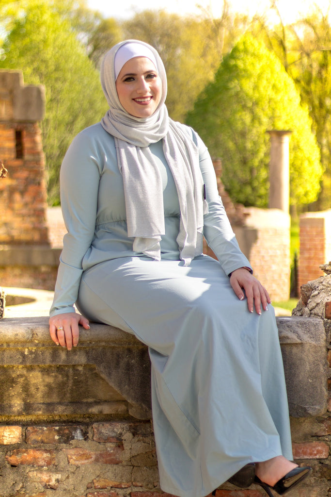 muslim woman in a sparkly silver jersey hijab and a light blue long sleeved maxi dress