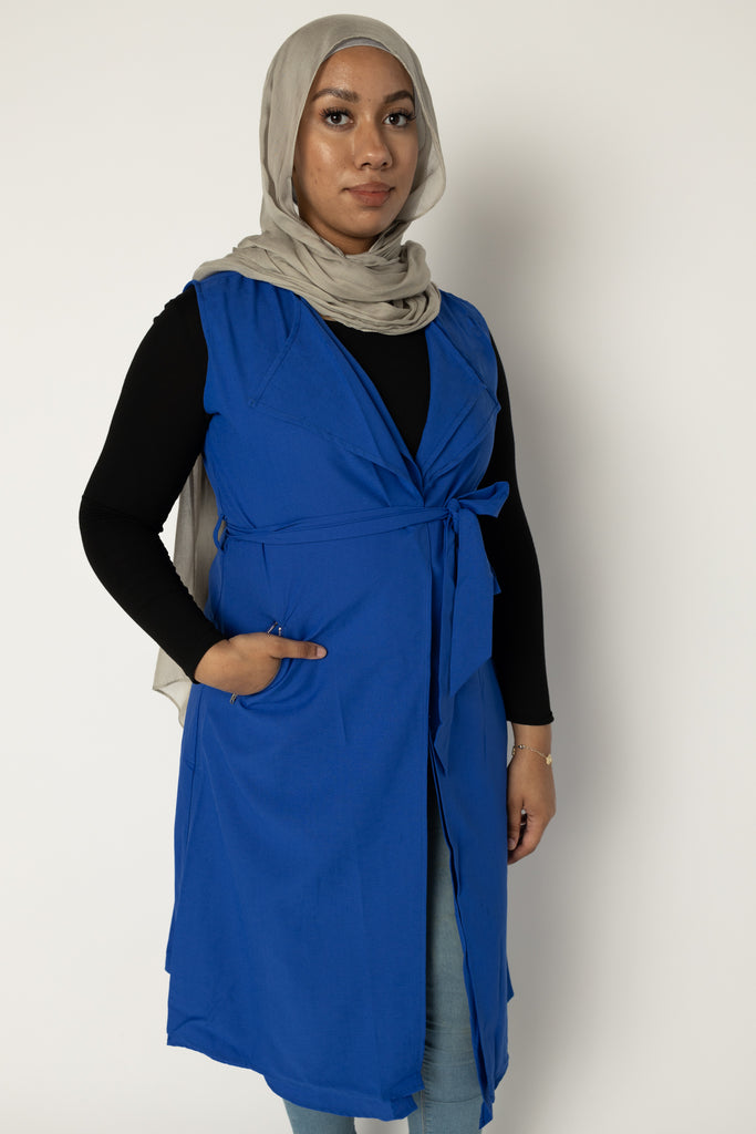 muslim woman wearing a royal blue sleeveless cascade jacket with zipper pockets and a white shimmer jersey hijab