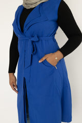 muslim woman wearing a royal blue sleeveless cascade jacket with zipper pockets and a white shimmer jersey hijab