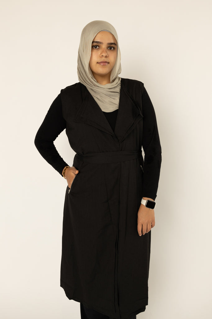 black cascade sleeveless vest with a waist belt and pocketsmuslim woman wearing a black sleeveless cascade jacket with zipper pockets and a blue shimmer jersey hijab