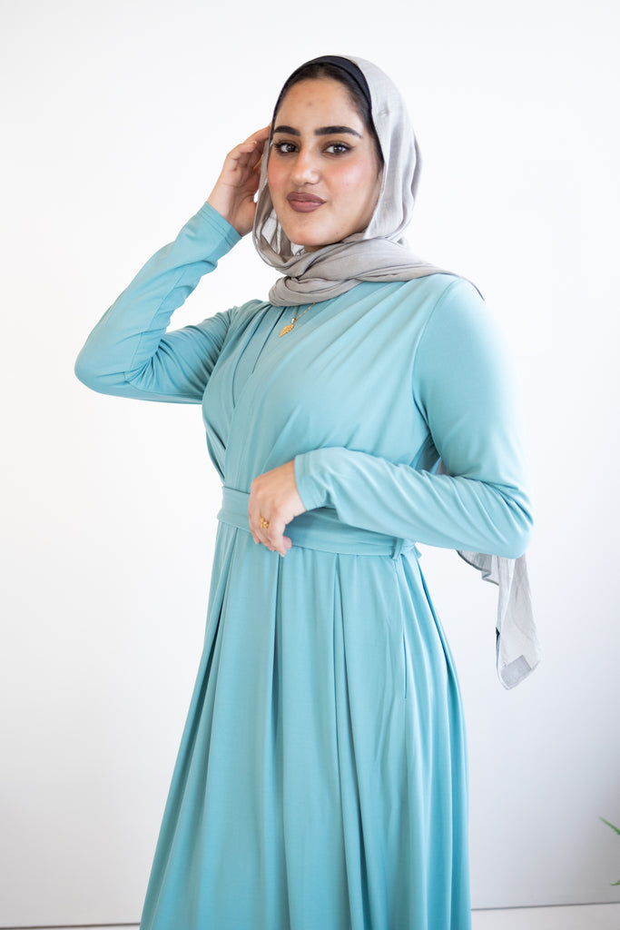 muslim woman wearing a criss cross teal blue long sleeve elegant maxi dress 