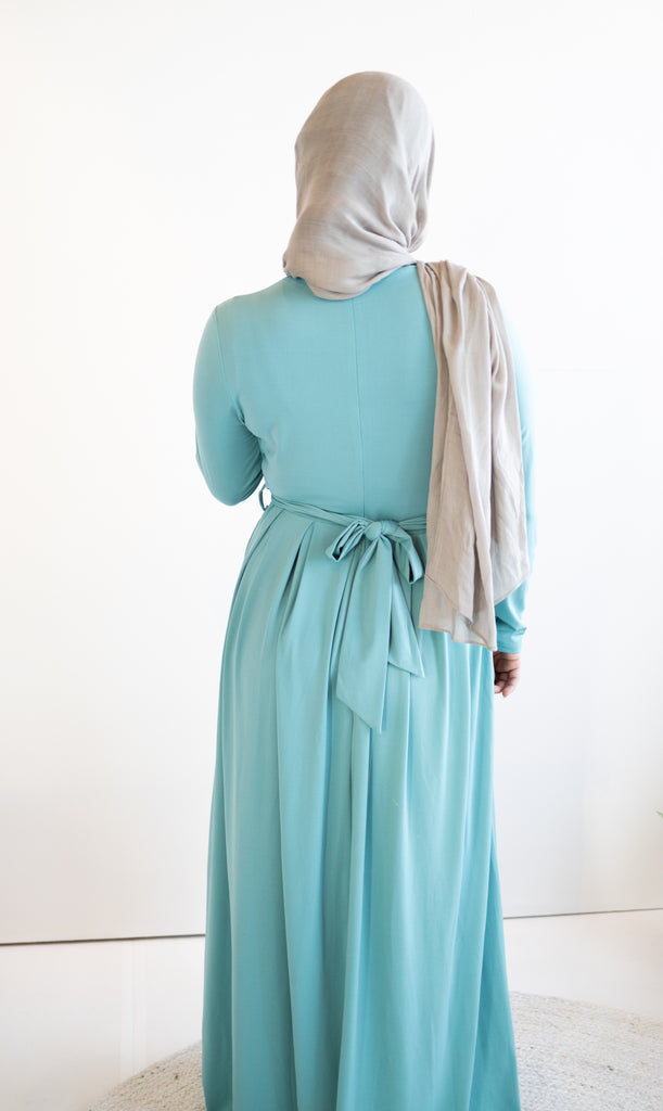muslim woman wearing a criss cross teal blue long sleeve elegant maxi dress 