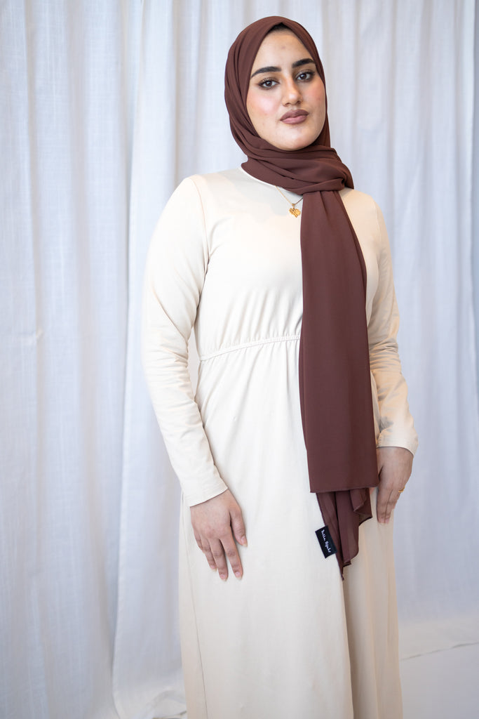 muslim woman in a creme long sleeve maxi dress and pearl hijab