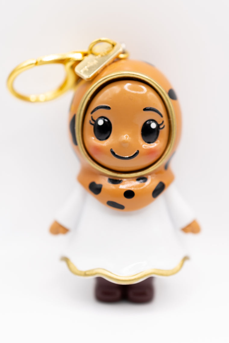 three hijabi figurines in different skin tones in cheetah print hijab on golden keychain