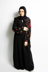 a black abaya with button clasps and pockets and watermelon and poppy tatreez palestinian embroidery along the sleeves 