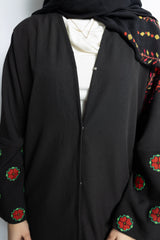 a black abaya with button clasps and pockets and watermelon and poppy tatreez palestinian embroidery along the sleeves 