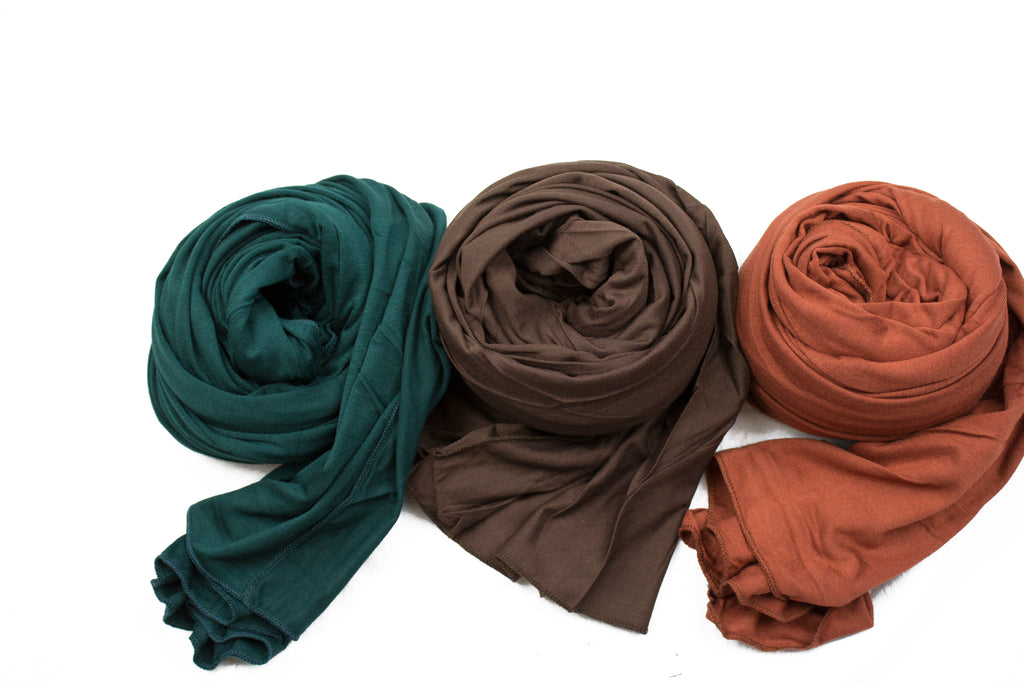 three jersey hijabs laid out next to each other in forest green, brown, and chestnut