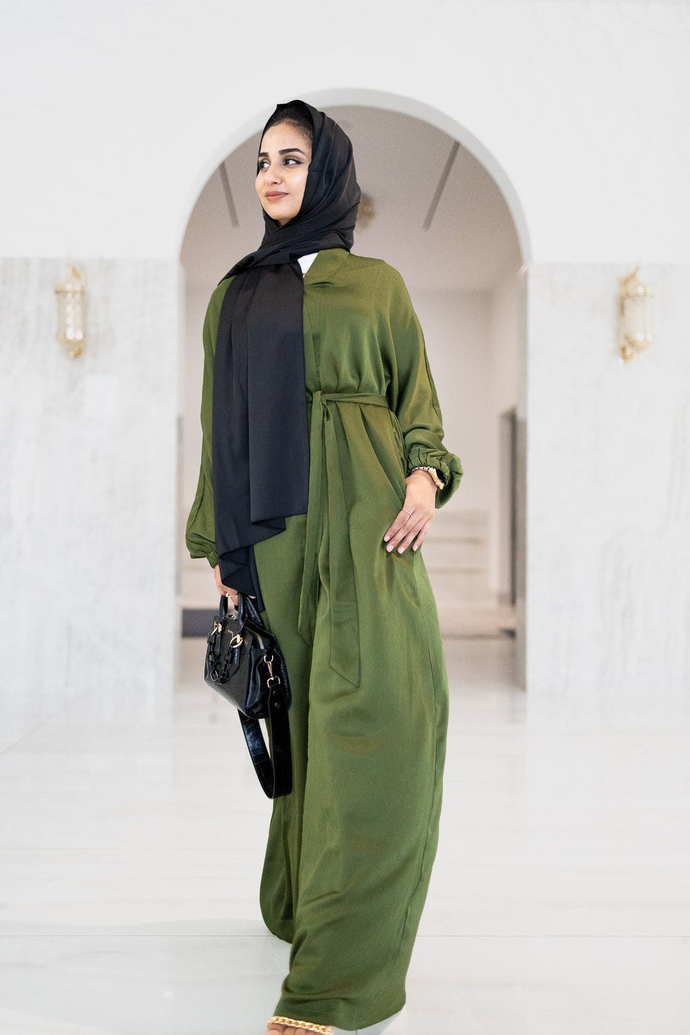 muslim woman wearing a beige long sleeve maxi dress with a long sleeve satin olive textured abaya with a waist tie and pockets