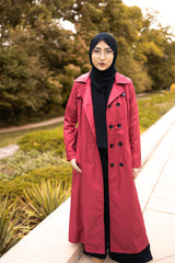 asian muslim woman wearing a black hijab and outfit with a maroon red maxi trench coat with black buttons