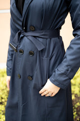 asian muslim woman wearing a black hijab and outfit with a navy blue maxi trench coat with black buttons