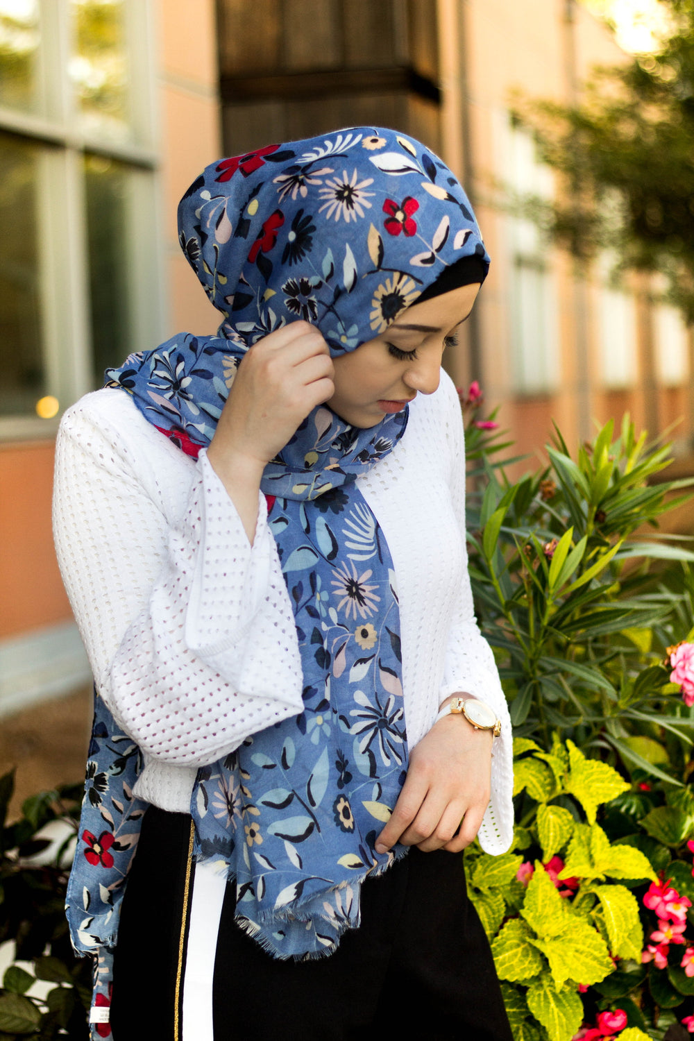muslim woman wearing a blue hijab with floral prints in multiple colors: yellow, red, blue, green, and pink