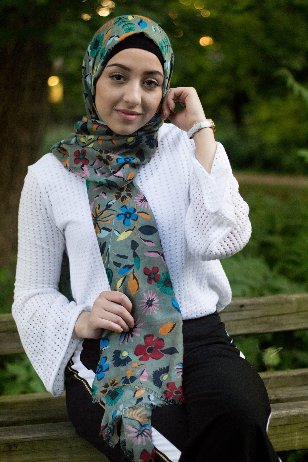 muslim woman wearing a green hijab with floral prints in multiple colors: yellow, red, blue, green,orange, and pink