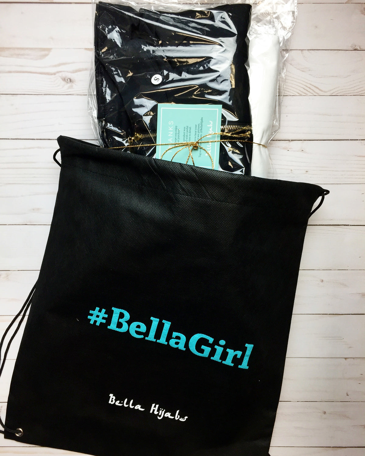 a black drawstring duster bag labeled #bellagirl with workout apparel inside