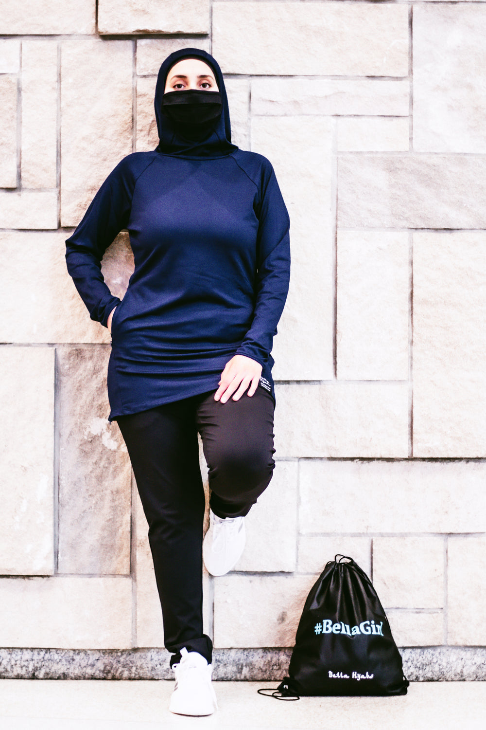 muslim woman wearing a covid-19 face mask and wearing a modest long sleeved workout top with hijab