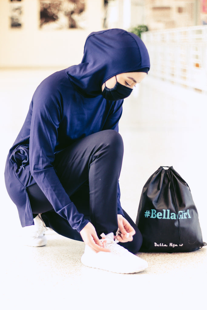 muslim woman tying her shoes and wearing a covid-19 face mask and wearing a modest long sleeved workout top with hijab