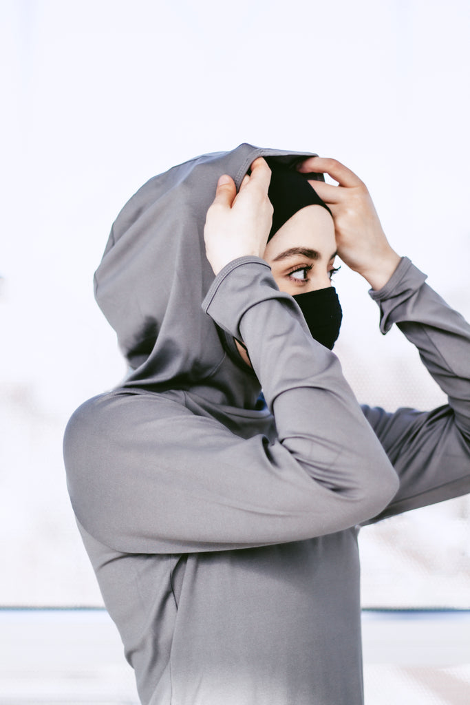 muslim woman putting on modest hooded workout top with hijab included