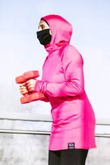muslim woman lifting red weights and wearing a pink workout top with hijab attached