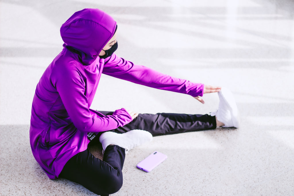 muslim woman stretching before a workout in modest exercise clothes and hijab