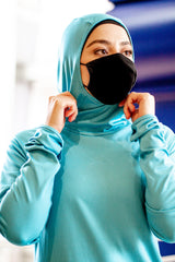 muslim woman wearing long sleeved modest workout top with a hoodie/hijab attached