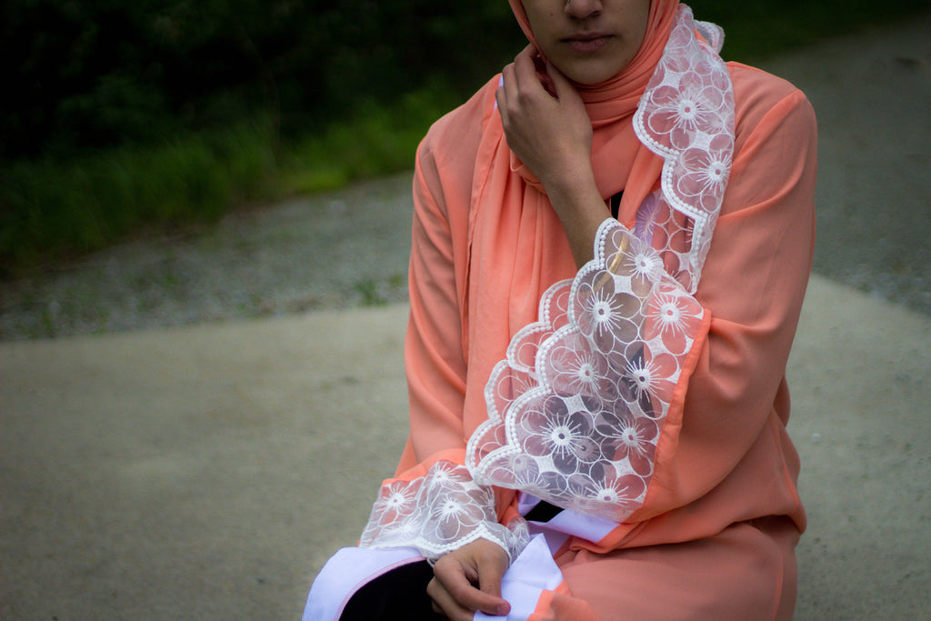 woman wearing an abaya in salmon embellished with lace sleeves and a matching hijab