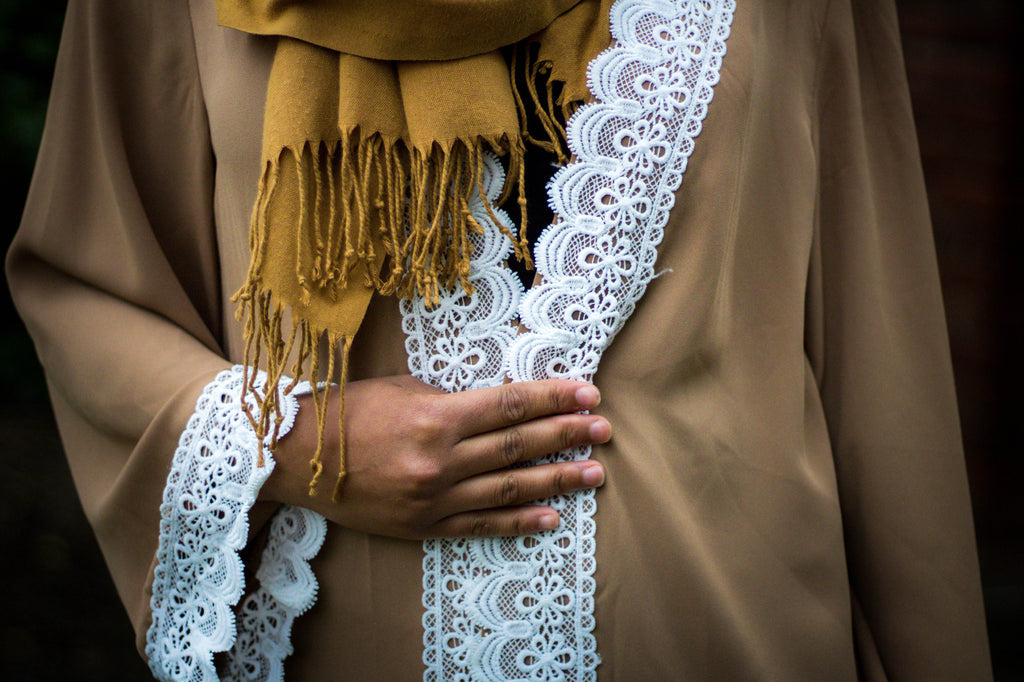 woman wearing an abaya in tan embellished with white lace sleeves