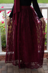 muslim woman wearing a maroon chiffon hijab with a black longsleeved top and maroon lace maxi skirt with pockets