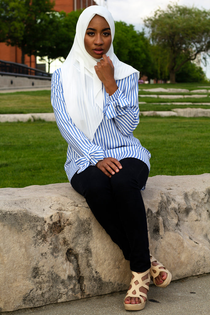 black muslim woman in white square hijab and white and blue striped bow sleeve blouse