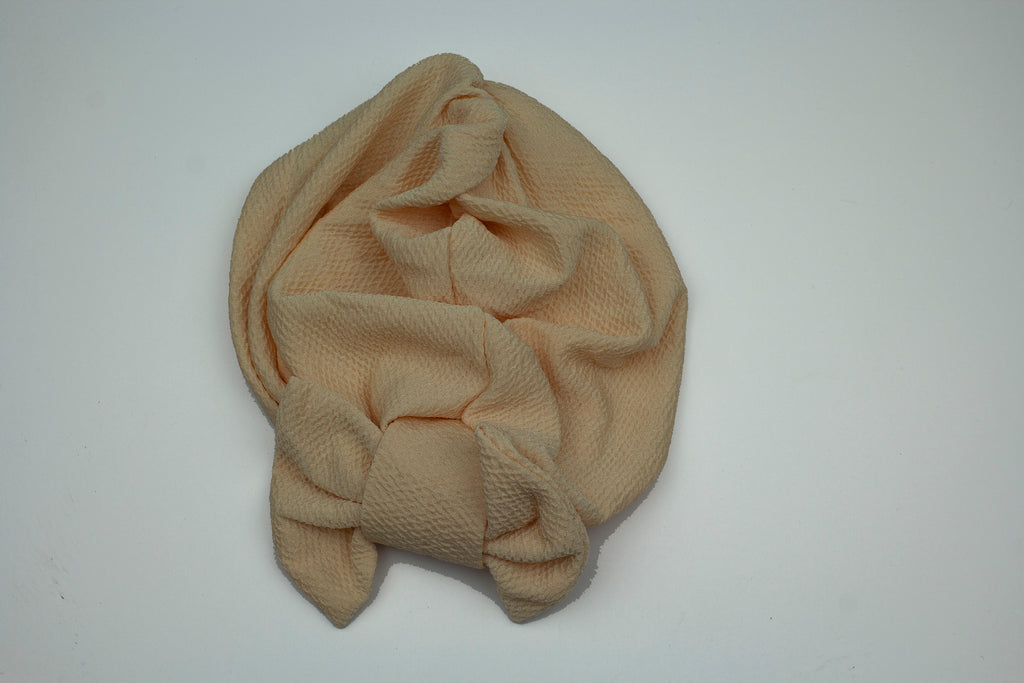 creme slip on turban with a large bow on the front