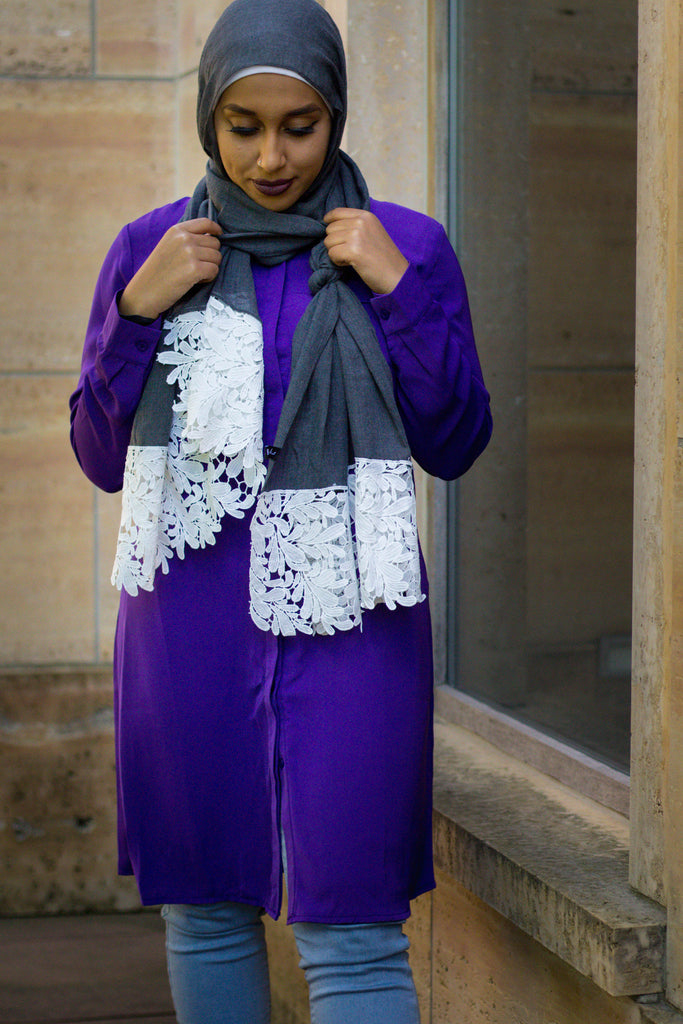 black muslim woman wearing a gray viscose hijab with white embroidered lace and a long sleeved modest blouse in purple