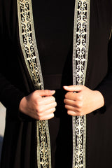 woman wearing a palestinian embroidered sleeveless kaftan with gold embroidery along the edges
