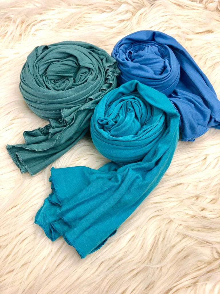 teal, turquoise, and periwinkle jersey hijabs laid out on fur rug