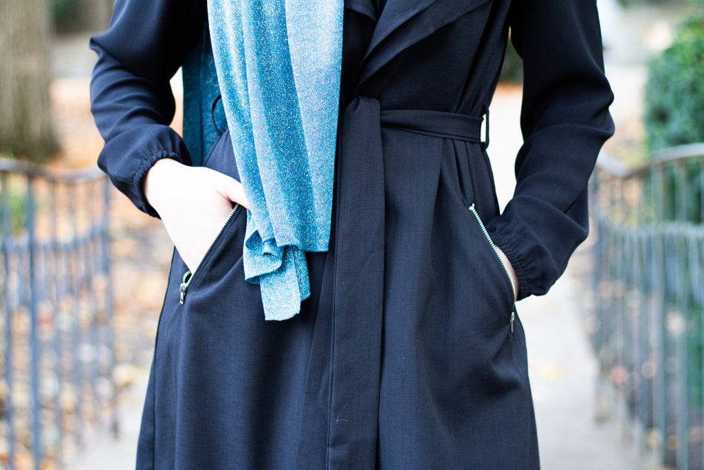 muslim woman wearing a black sleeveless cascade jacket with zipper pockets and a blue shimmer jersey hijab