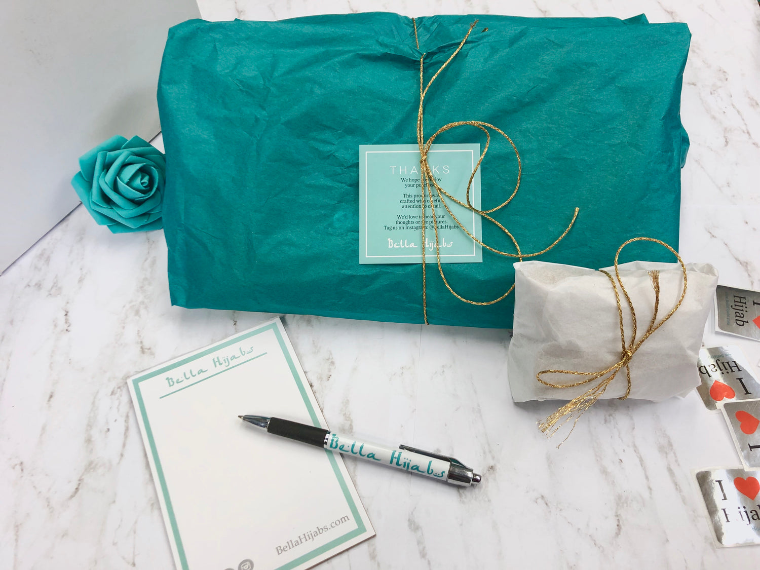 a flatlay of gift wrapped products in teal and white tissue paper