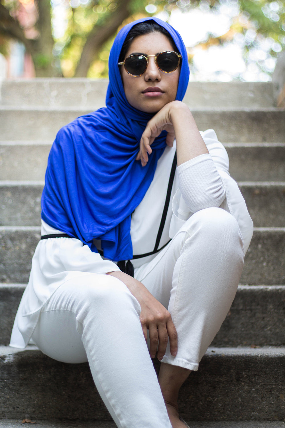 muslim woman wearing all white and a royal blue jersey hijab and sunglasses