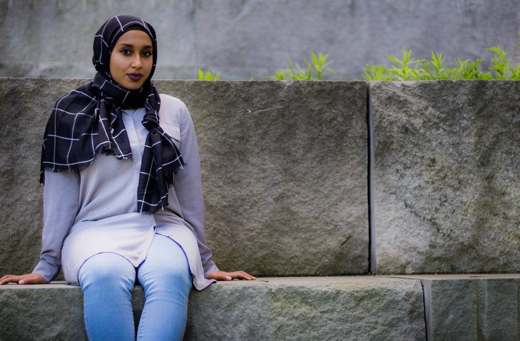 black muslim woman wearing a black and white grid viscose hijab and a long sleeved modest blouse in silver