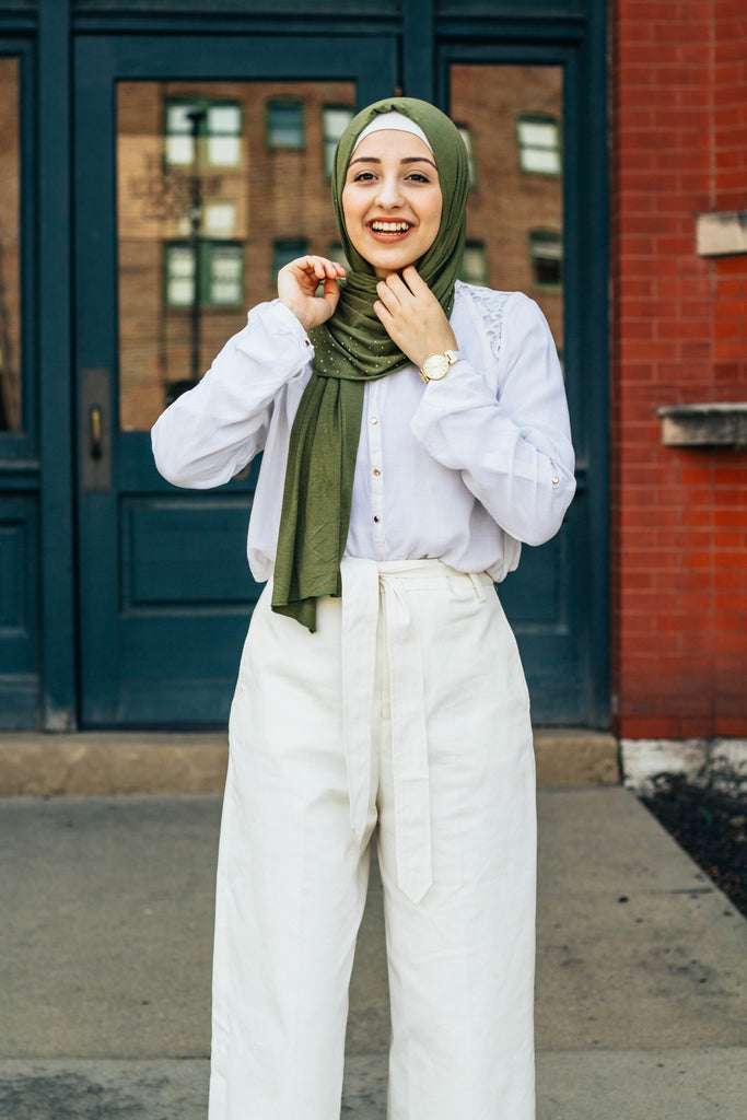 muslim woman wearing white top and pants with a beaded olive green hijab
