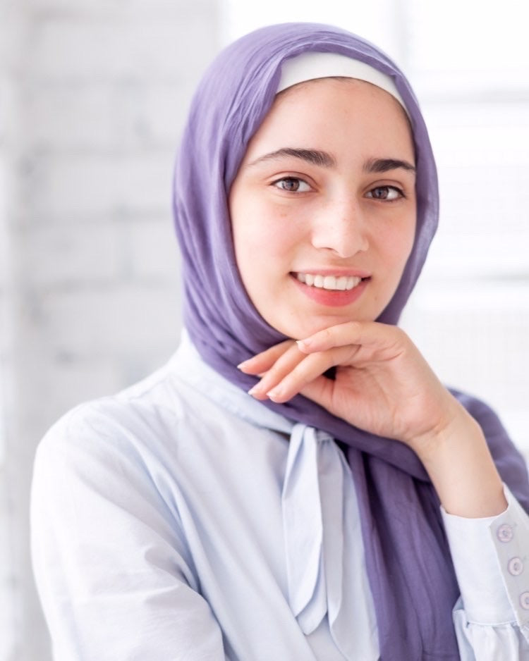 muslim woman wearing a purple modal hijab and white long sleeved top