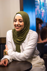 muslim woman wearing white top and pants with a beaded olive green hijab
