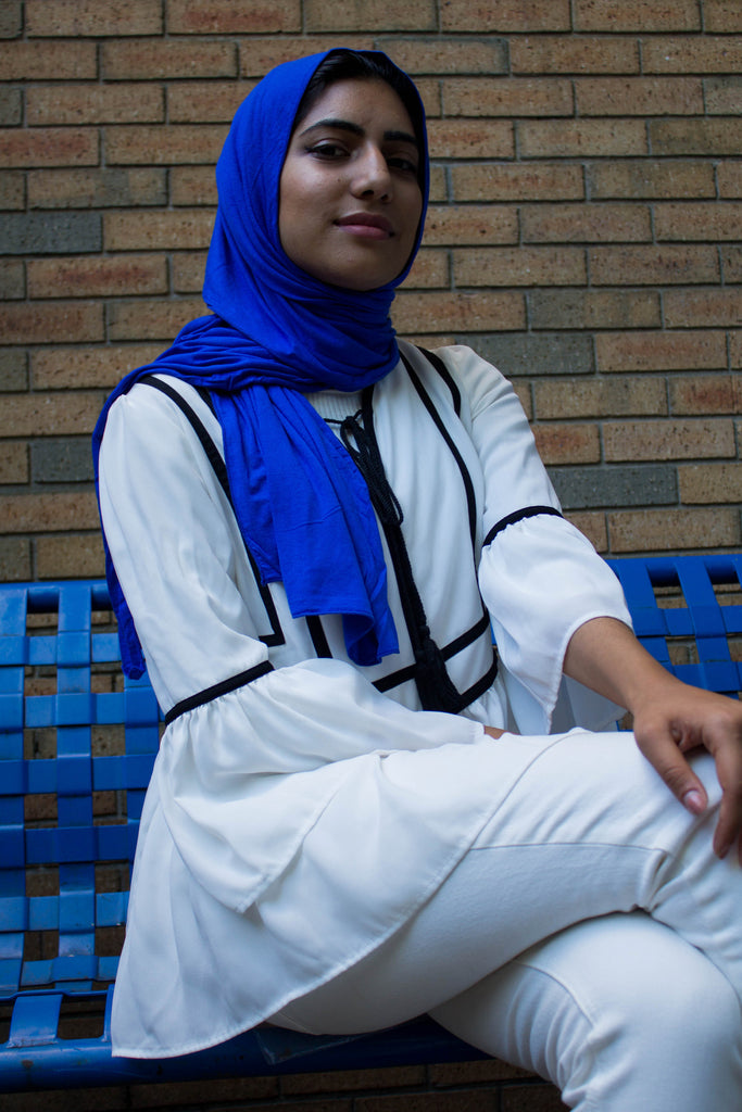 muslim woman wearing all white and a royal blue jersey hijab
