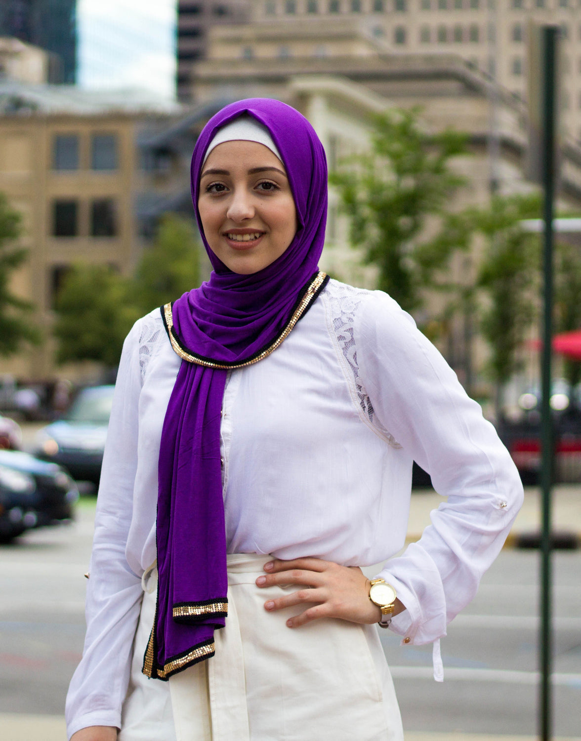 muslim woman wearing white top and white pants and purple jersey hijab with a gold trim