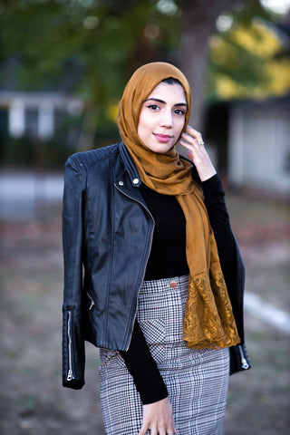 muslim woman wearing a mocha brown modal lace hijab modal hijab with lace on the ends and a leather bomber jacket and pencil checkered skirt
