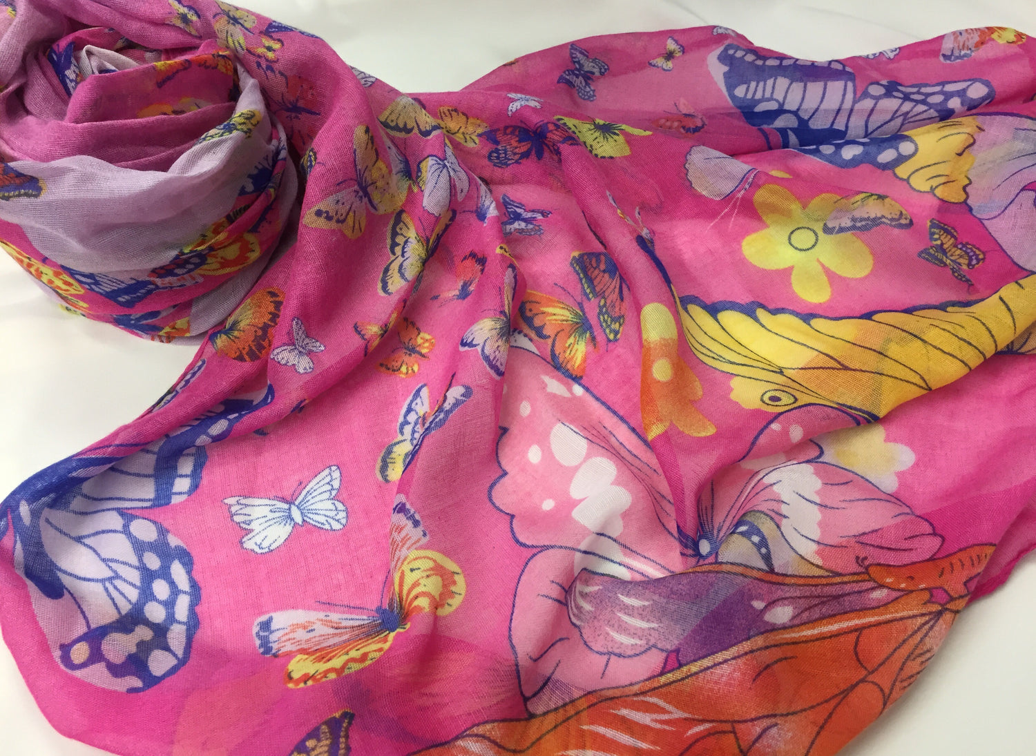 soft pink hijab printed with butterflies in green, pink, red, yellow, purple, and blue
